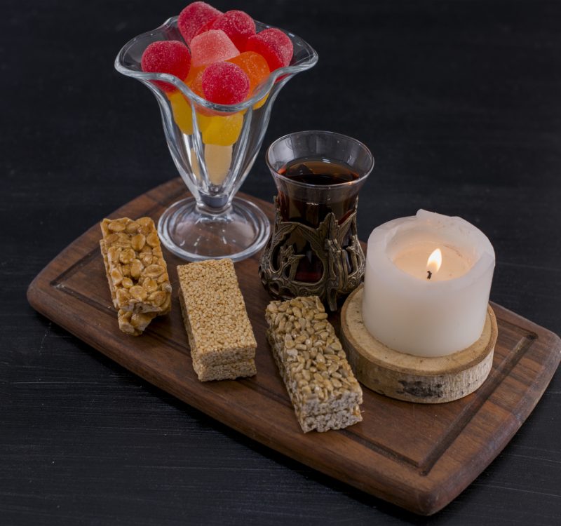 A glass of tea served with marmelades and sesame waffles on blue background. High quality photo