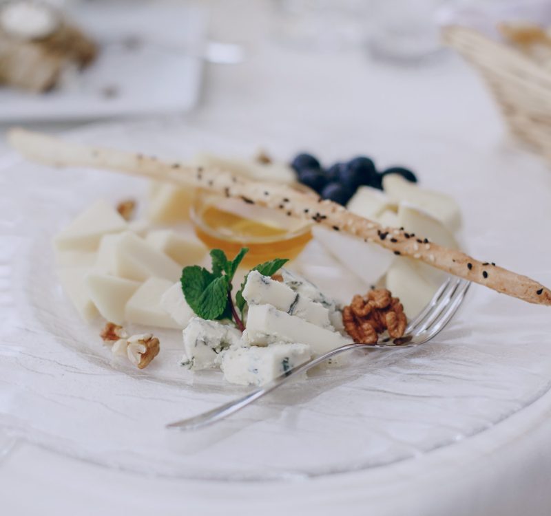 On the wedding table there is food, forks, spoons, glasses, a knife and napkins